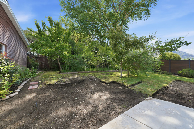 3120 North Apache Way Provo, UT 84604 - Photo 49 of 58 Expansive backyard featuring a partial concrete patio, areas of established lawn, mature trees, a low privacy fence, and brick exterior elements