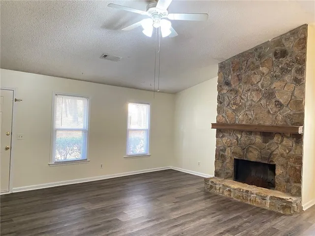 an empty room with wooden floor cabinet and windows