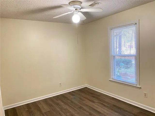 an empty room with wooden floor and fan