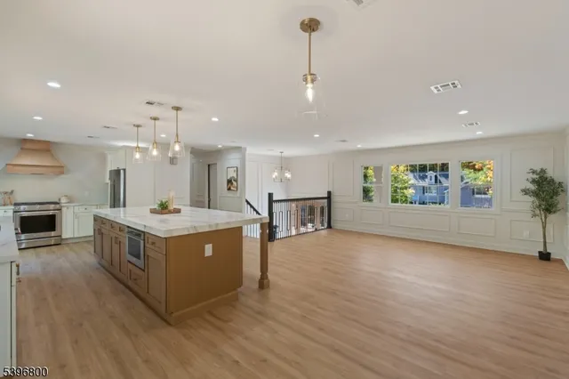 a large kitchen with stainless steel appliances granite countertop a large center island a stove a sink and a fireplace