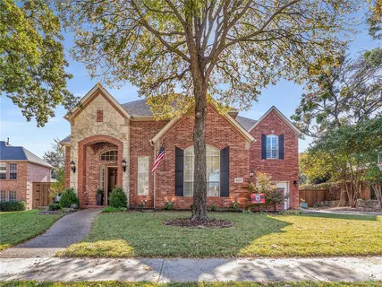 a front view of a house with a garden and trees