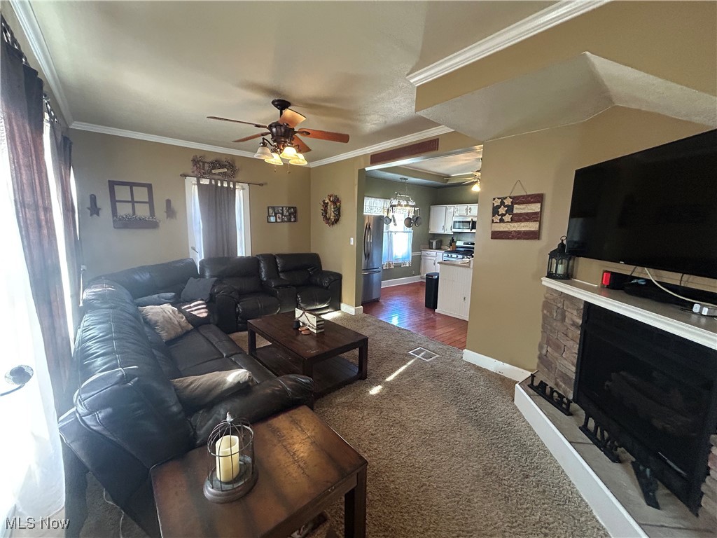 150 West Athens Road Roseville, OH 43777 - Photo 4 of 17 Living room with ceiling fan, crown molding, a fireplace, dark colored carpet, and a chandelier