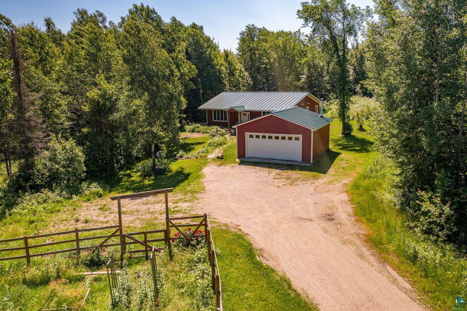 9734 Alango Road Angora, MN 55703 - Photo 30 of 41 Red-sided residence featuring a green metal roof and an attached two-car garage