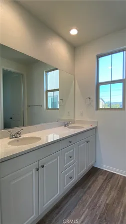 a bathroom with a granite countertop double vanity sink large mirror and a window
