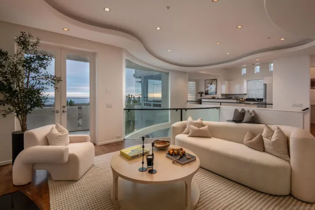 an aerial view of a city with lots of residential buildings and ocean view in back