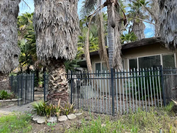 a view of a brick house with large trees and plants