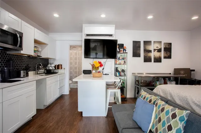 a kitchen with stainless steel appliances granite countertop a stove top oven a sink a dining table and chairs with wooden floor