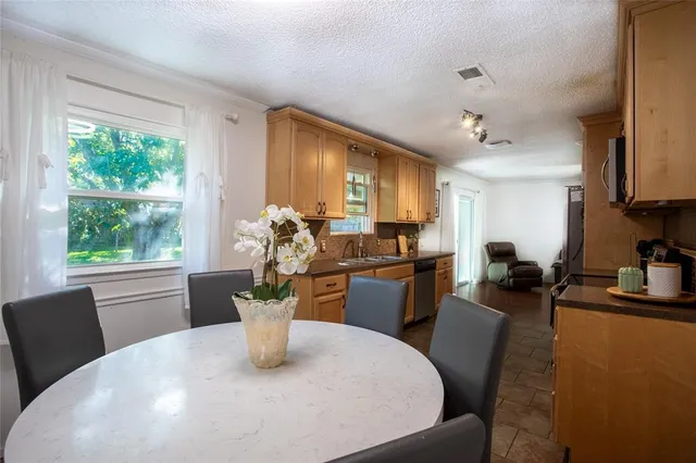 a dining room with furniture a potted plant and a kitchen view