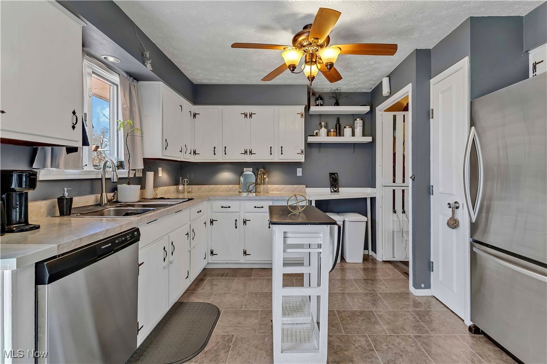 7760 York Road Cleveland, OH 44130 - Photo 7 of 39 Kitchen with a ceiling fan, a sink, stainless steel appliances, a textured ceiling, and white cabinetry