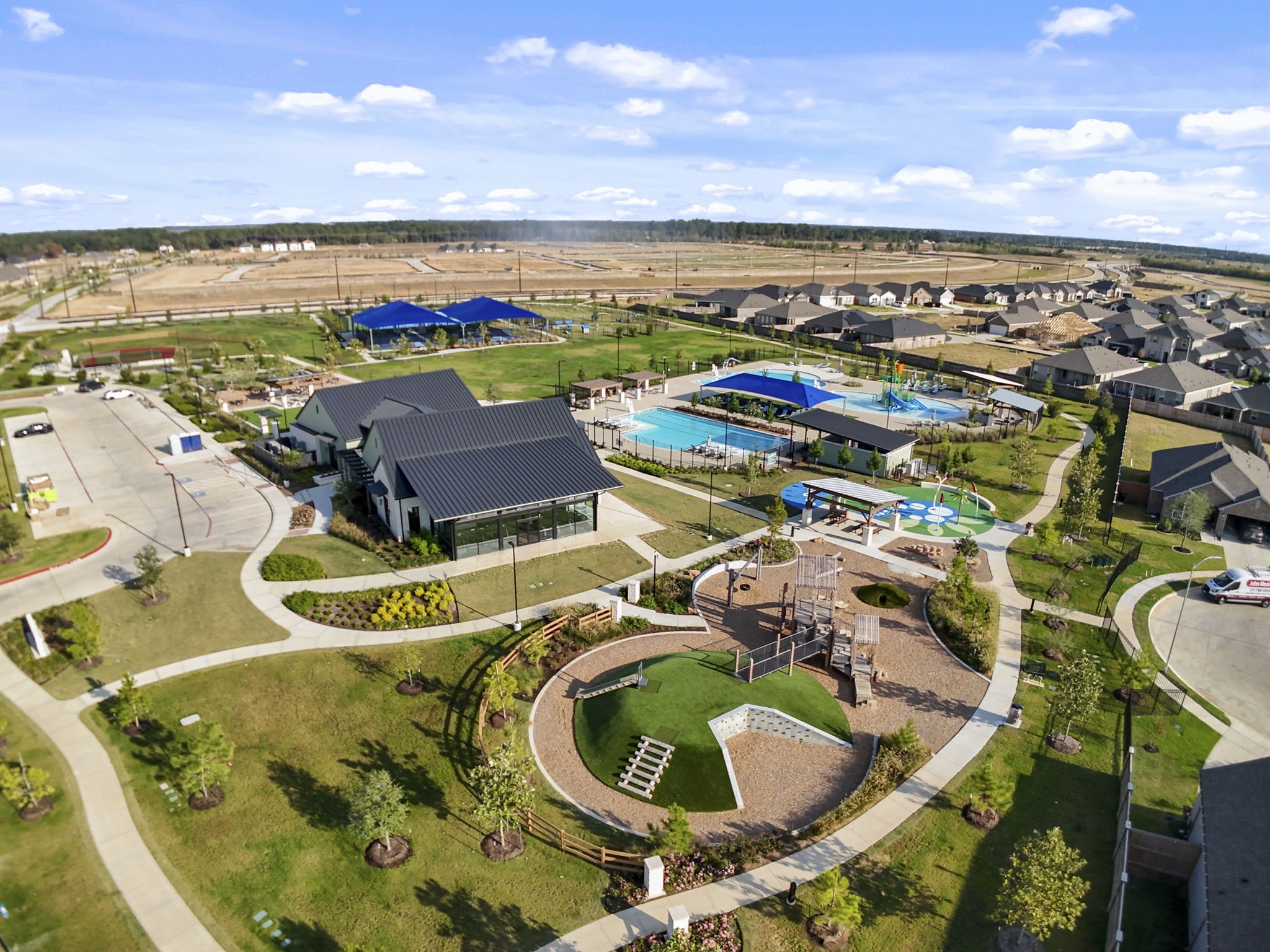 22218 Rome Breeze Drive Hockley, TX 77447 - Photo 33 of 34 A bird’s-eye view of the community center highlights its family-friendly amenities including playgrounds, green parks, and a beautiful pool area surrounded by landscaped walking trails.