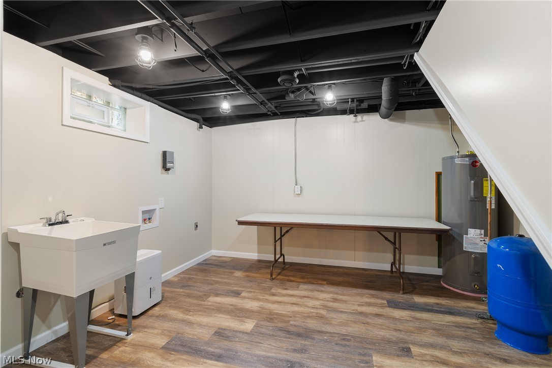 1075 Northeast River Road Lake Milton, OH 44429 - Photo 29 of 34 Finished basement space featuring wood-finish flooring, painted exposed ceiling joists, and a utility sink