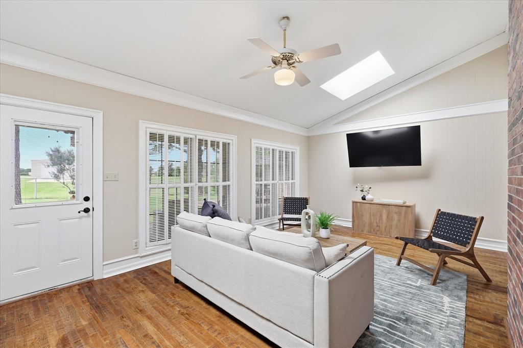 6955 Hawk Road Flower Mound, TX 75022 - Photo 11 of 40 Vaulted ceiling sunroom featuring wood-finish flooring, a ceiling fan, and a skylight