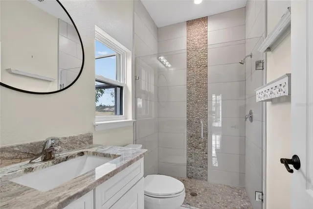 a bathroom with a granite countertop sink toilet and mirror