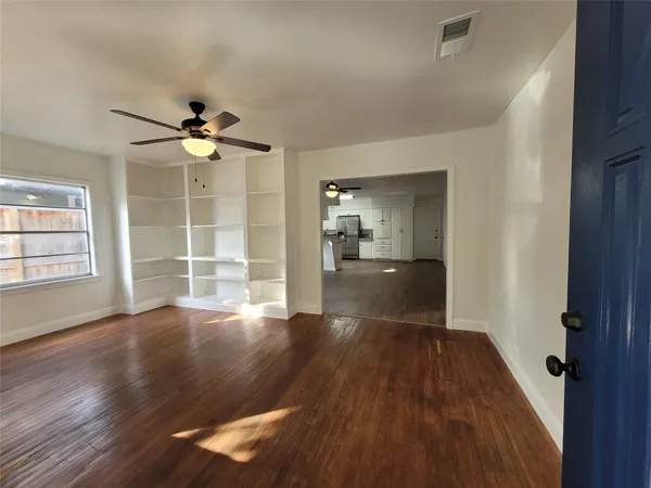 a view of an empty room with wooden floor and a window