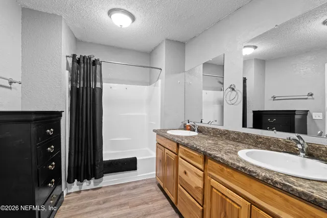 a bathroom with a granite countertop double vanity sink and mirror