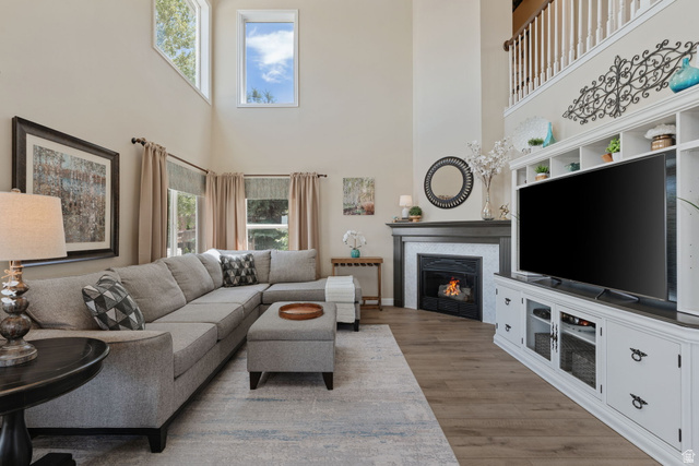 14883 Tooele Lane Draper, UT 84020 - Photo 16 of 49 Spacious living area featuring a two-story ceiling, multiple large windows, and wood-finish flooring
