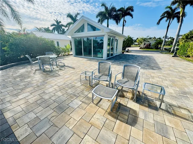 a view of a patio with table and chairs potted plants and palm trees