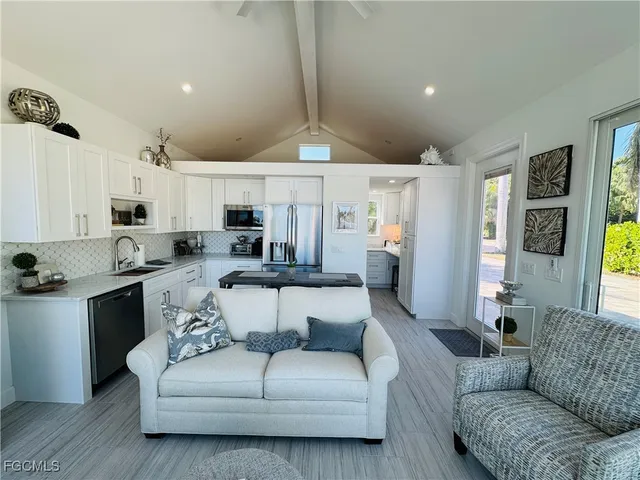 a living room with furniture white walls and kitchen view