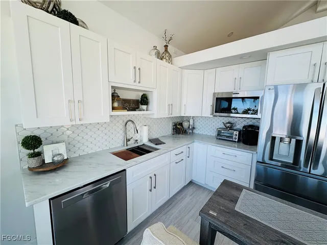 a kitchen with a sink white cabinets and stainless steel appliances