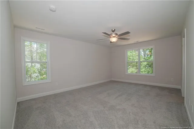 an empty room with windows and fan