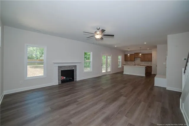 an empty room with wooden floor a kitchen view and a fireplace