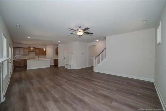 an empty space with wooden floor and a kitchen