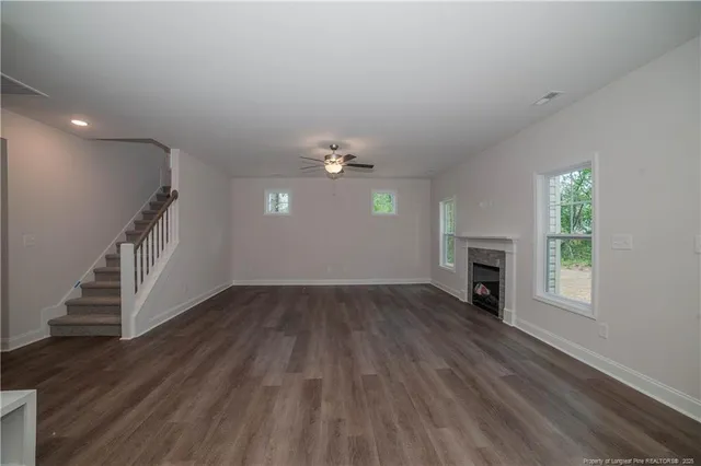 an empty room with wooden floor fireplace and windows