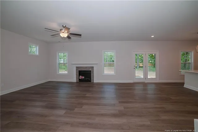 a view of an empty room with wooden floor fireplace and a window