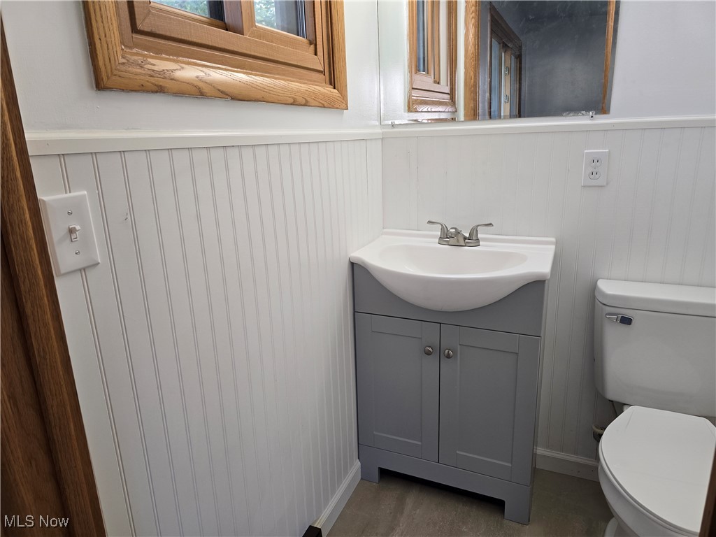 67 Moore Road Akron, OH 44319 - Photo 12 of 15 Bathroom featuring vanity, toilet, wood-type flooring, and wood walls