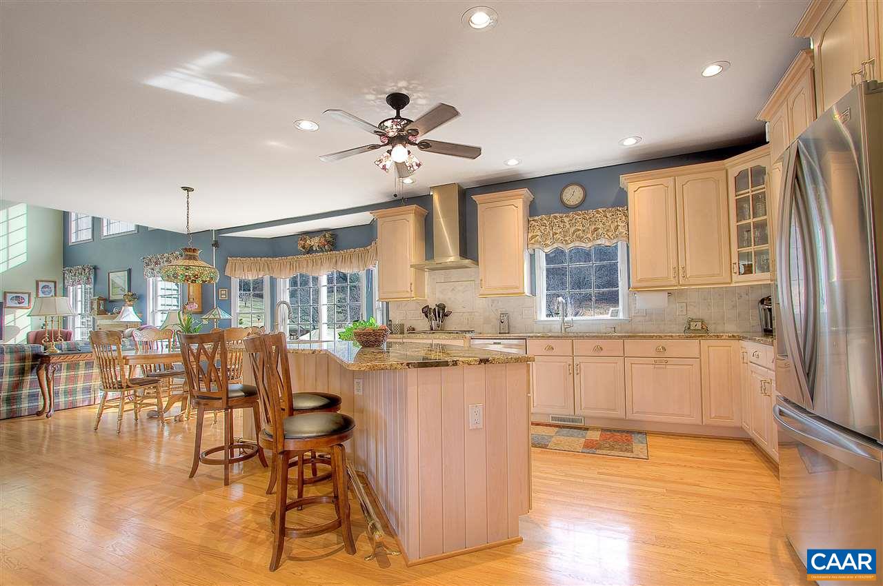 9075 Critzer Shop Road Afton, VA 22920 - Photo 13 of 32 a open kitchen with granite countertop a stove a sink a dining table and chairs with wooden floor