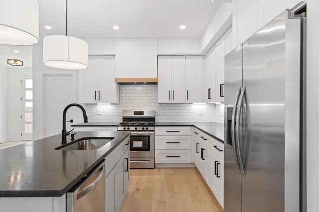 a kitchen with kitchen island stainless steel appliances granite countertop a sink a stove and a refrigerator