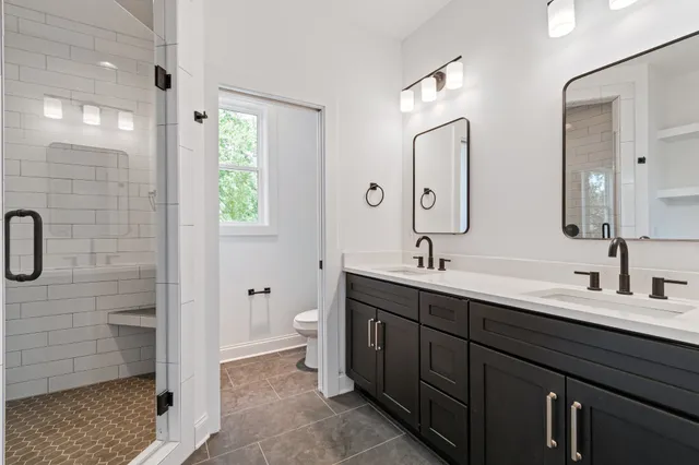 a bathroom with a double vanity sink a toilet and shower