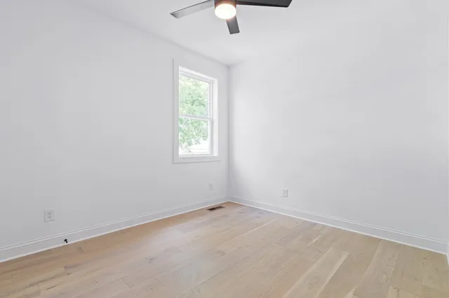 an empty room with a window and a ceiling fan