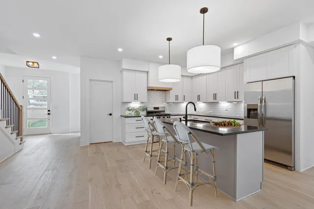 a kitchen with stainless steel appliances granite countertop a sink a stove a refrigerator and island with wooden floor