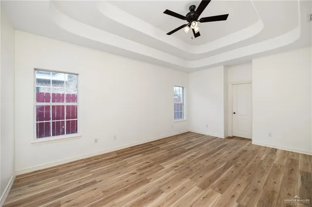 a view of empty room with wooden floor and ceiling fan