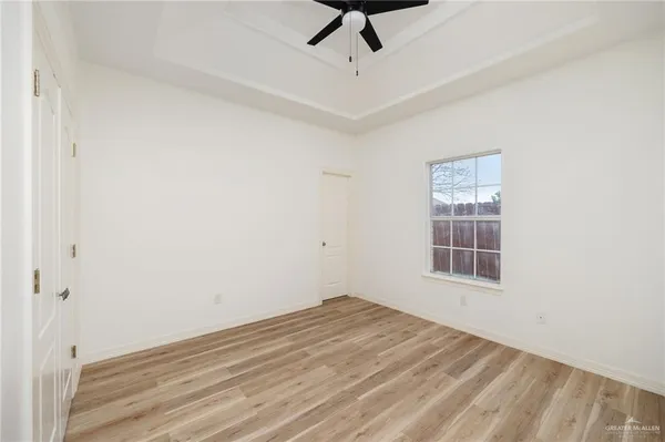 a view of empty room with wooden floor and fan