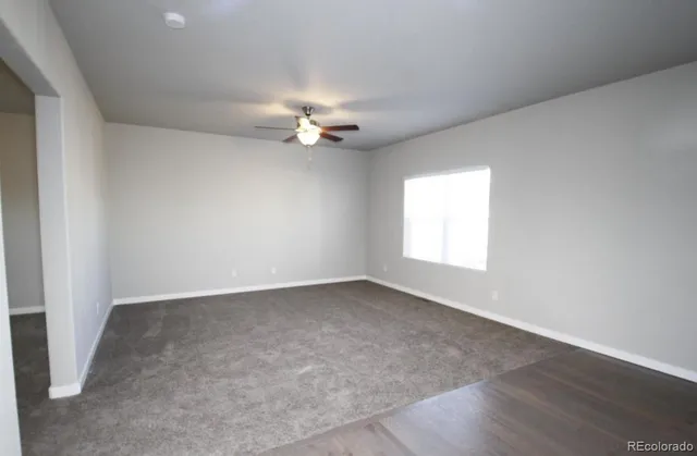 an empty room with a window and a fan