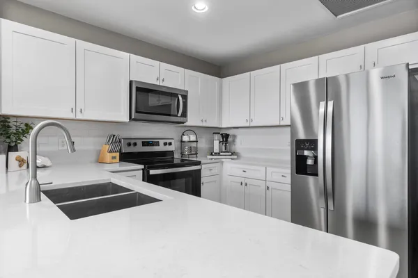 a kitchen with granite countertop a refrigerator stove and microwave