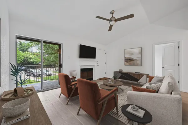 a living room with furniture a fireplace a flat screen tv and a large window
