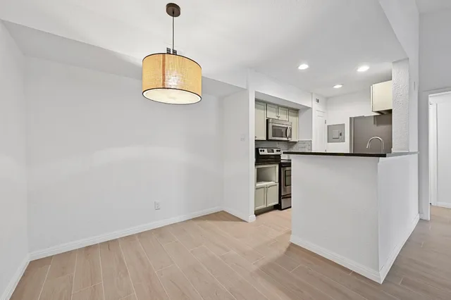 a kitchen with stainless steel appliances granite countertop a refrigerator a oven and a wooden floors