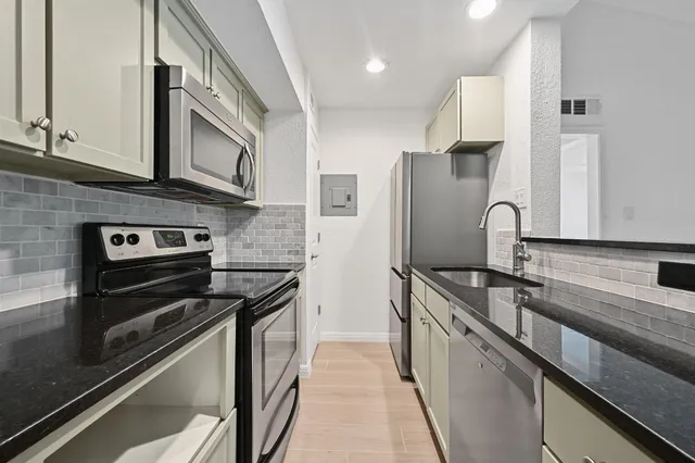 a kitchen with stainless steel appliances granite countertop a stove a sink and a refrigerator