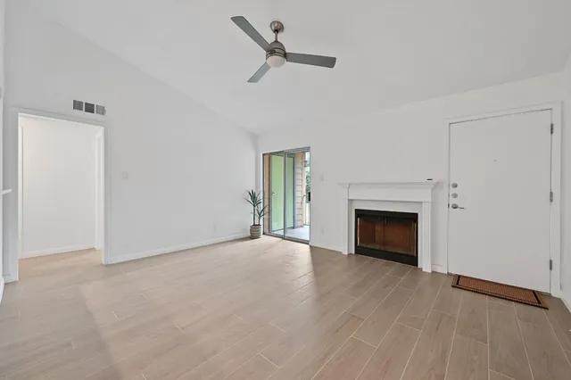 an empty room with fireplace and a ceiling fan