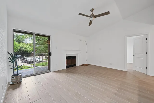 an empty room with floor to ceiling windows and ceiling fan