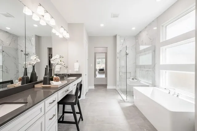 a large bathroom with a double vanity sink a large mirror and a bathtub