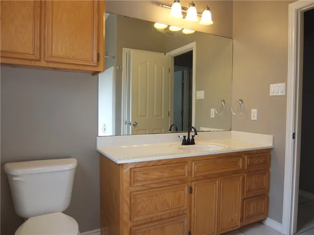 a bathroom with a granite countertop toilet sink and mirror