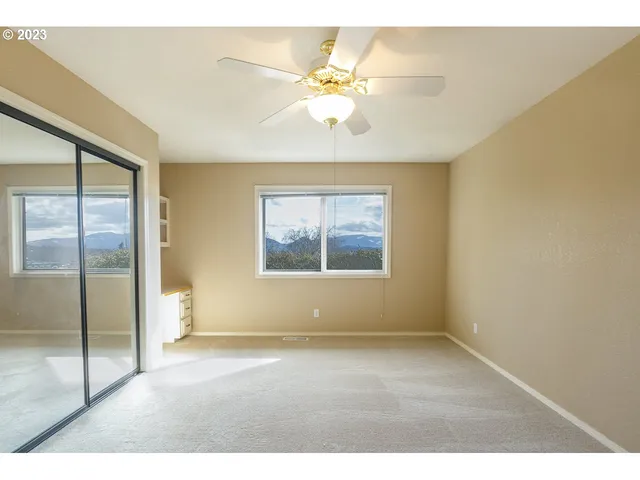 an empty room with windows and chandelier fan