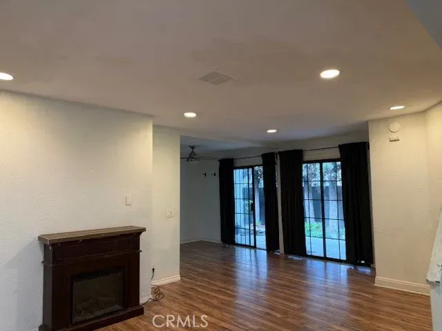a view of an empty room with wooden floor and a fireplace