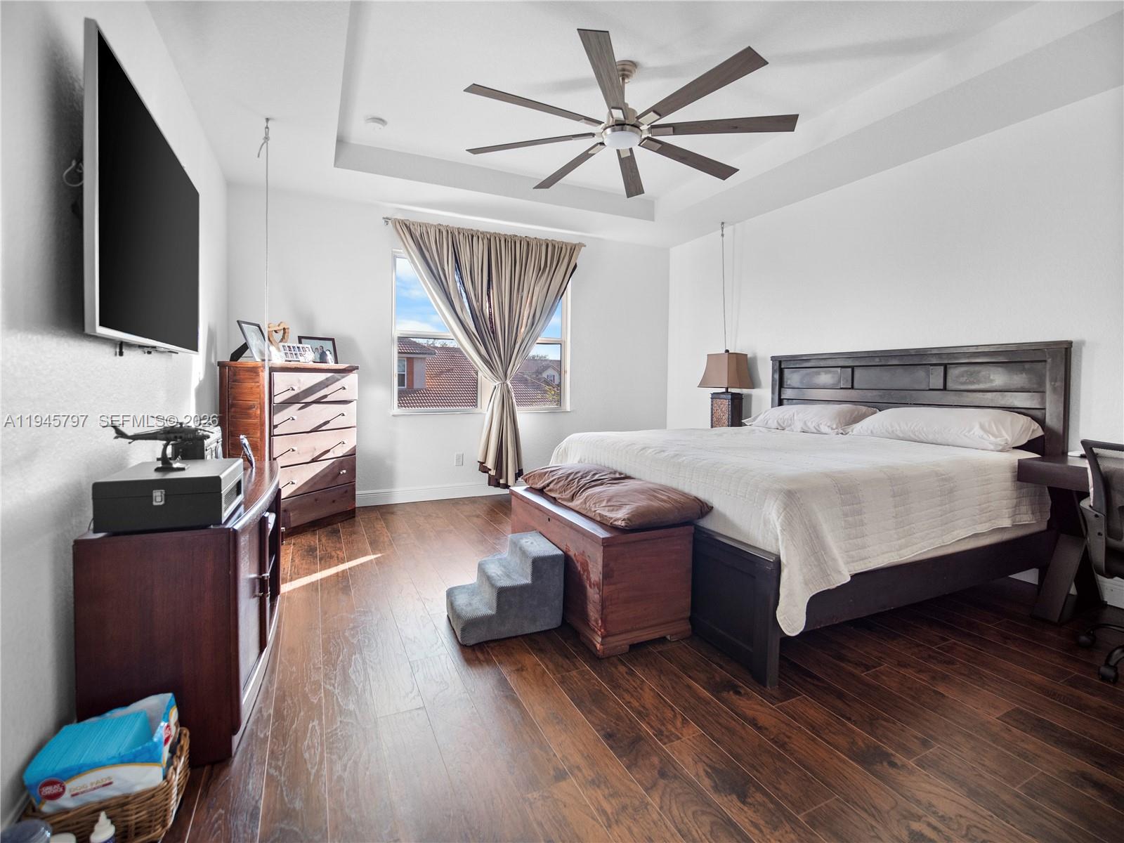 10552 Belfry Circle Orlando, FL 32832 - Photo 19 of 32 a bedroom with a bed wooden floor and a flat screen tv