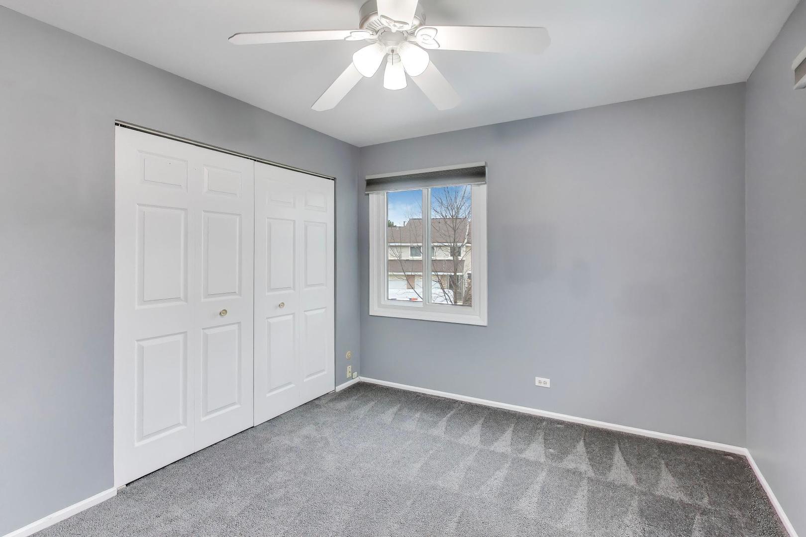 1096 Pine Tree Circle North Buffalo Grove, IL 60089 - Photo 20 of 25 an empty room with a chandelier fan and windows
