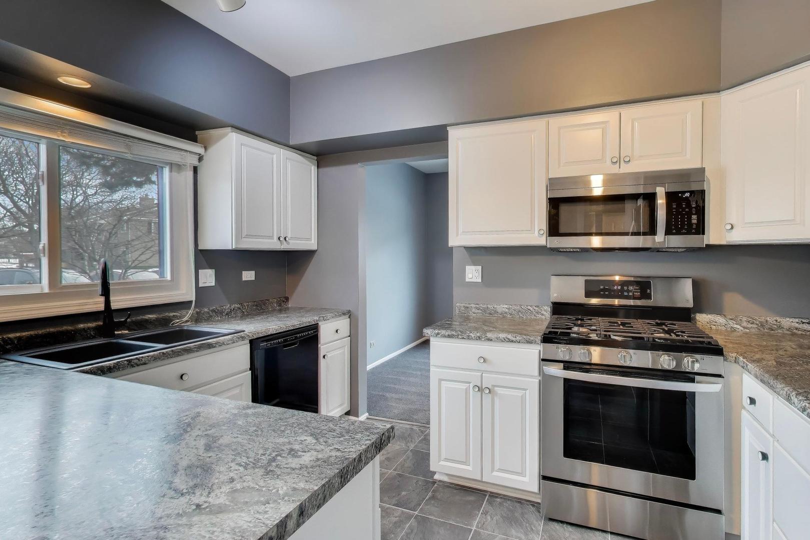 1096 Pine Tree Circle North Buffalo Grove, IL 60089 - Photo 7 of 25 a kitchen with granite countertop a stove a sink and a microwave